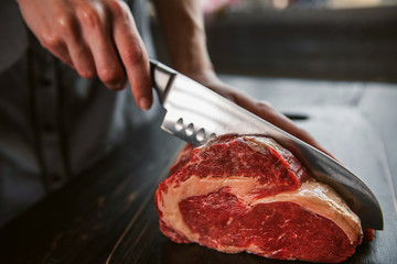 cook cuts raw meat for steaks