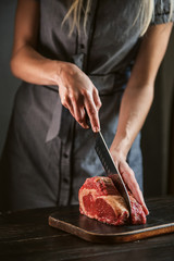 cook cuts raw meat for steaks