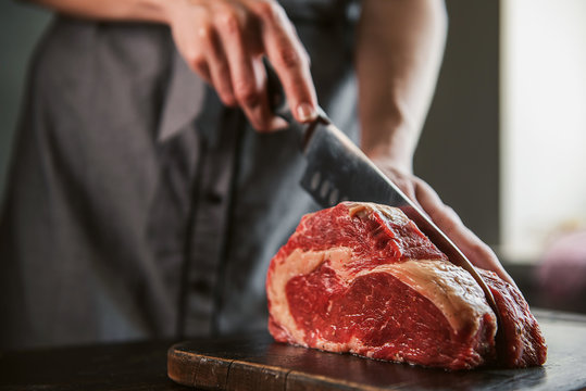 cook cuts raw meat for steaks