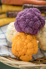 Bunter Blumenkohl in Lila, Orange und Weiß auf Geschirrtuch in Korb auf Pastell Mint Grün...