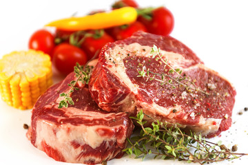 Obraz premium set for cooking a festive dinner for two. two raw marbled beef steaks, spices, vegetables and a grill pan with a meat fork. all on a white background