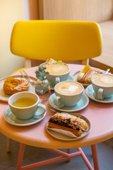 Cafe table with cups of coffee, eclairs and cake