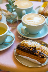 Cafe table with cups of coffee, eclairs and cake