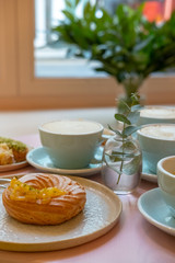 Cafe table with cups of coffee, eclairs and cake