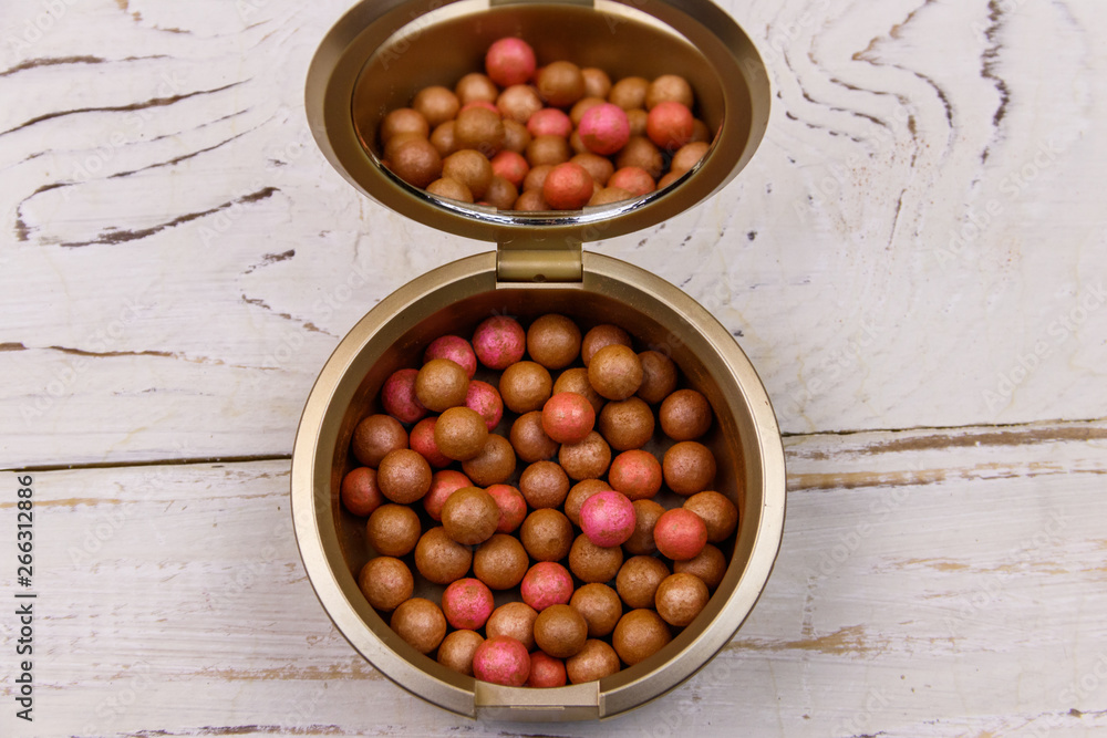 Wall mural rouge balls in the open round plastic container with mirror inside lid on a white wooden background