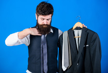 The perfect tie for his business casual style. Hipster matching necktie to business outfit. Elegant business man holding classy necktie and formal suit jacket. Bearded man wearing business dress code