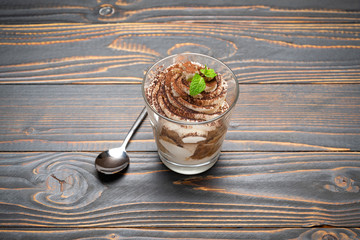 portion of Classic tiramisu dessert in a glass on wooden background
