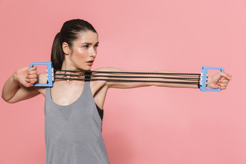 Beautiful young pretty fitness woman make sport exercises with equipment isolated over pink wall background.