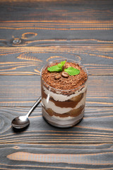 portion of Classic tiramisu dessert in a glass on wooden background