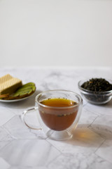 Green tea with jasmine in a transparent mug on a light background. Vertical orientation