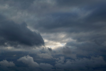 Heavy thunderclouds filled the sky. In the center of the far a small gleam among dark rain cloud. Bad and dangerous weather. Weather forecast, meteorology. Background, backdrop.