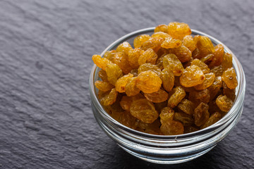 golden raisins on a dark stone background