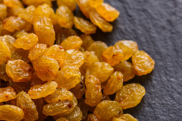 golden raisins on a dark stone background