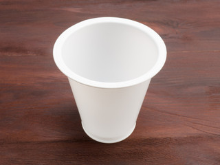 Plastic white glass on a brown wooden background
