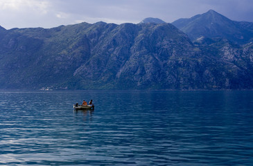Scenic view of the sea and mountains in the Bay of Kotor, a boat in the sea, dawn sky