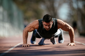 Fitness man doing push ups outdoor. Athlete training.