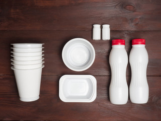 Two plastic white bottles, banks, glasses on a brown wooden background