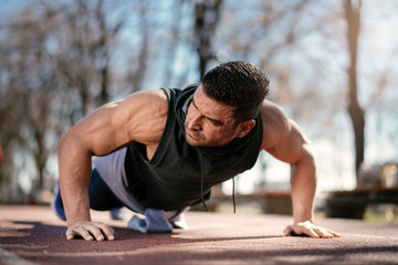 Fitness man doing push ups outdoor. Athlete training.