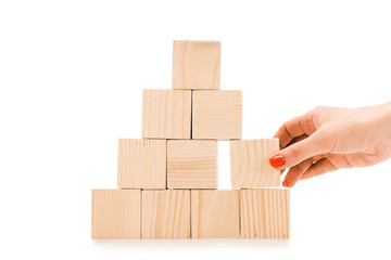 cropped view of woman picking up one wooden block with copy space from pyramid isolated on white