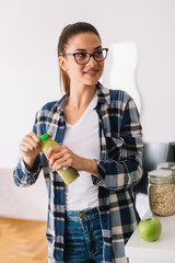 Young woman drinking smoothie at home