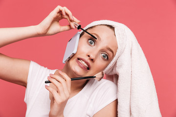 Portrait of positive young woman 20s wrapped in white towel after shower applying cosmetics with makeup brush