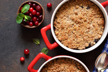 Crumble with cranberries and other berries, nuts on the kitchen table. View from above.