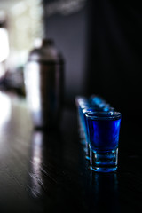 Blue cocktail in shots and shaker standing on a bar counter