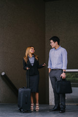 A couple of teammate talking about a work before they go home. They look very attractive in their office attire.