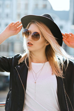 Street shot of young lovely girl wearing sunglasses and black hat