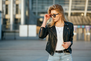 Lifestyle portrait of young wonderful woman wearing mirror sunglasses and leather jacket. Empty space
