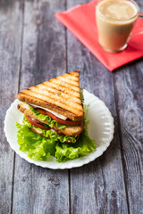 Sandwich with cheese, tomato, cucumber, sausage and lettuce on a wooden background. Vertical orientation