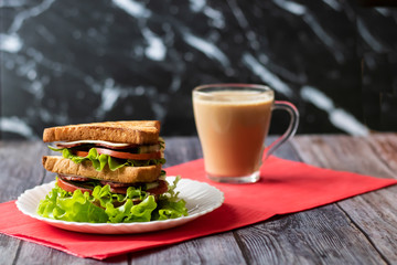 Sandwich with cheese, tomato, cucumber, sausage and salad on wooden background. Coffee with milk Horizontal orientation