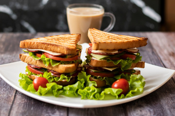 Sandwich with cheese, tomato, cucumber, sausage and salad on wooden background. Coffee with milk Horizontal orientation