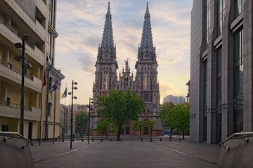 Fototapeta na wymiar Spring morning landscape view of astonishing Saint Nicholas Roman Catholic Cathedral (House of Organ Music) during sunrise. View of the cathedral between the high-rise buildings. Kyiv, Ukraine
