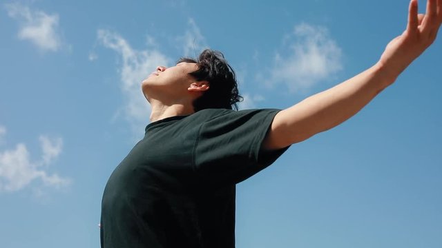 Man relaxing on the freedom with raised hands over blue sky background