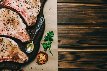 Raw fresh meat pork steak and seasonings on a dark wooden background board honey tomato board
