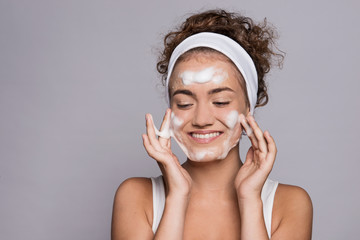 Portrait of a young woman cleaning face in a studio, beauty and skin care.