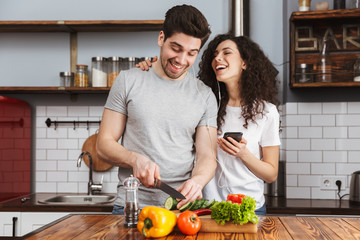 Portrait of happy couple listening to music together while cooking salat in kitchen at home