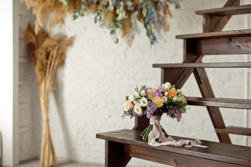 Fototapeta na wymiar Wedding bouquet of pink roses with a lilac on a blurred background on a wooden staircase