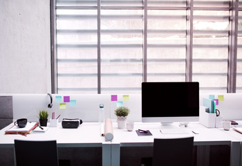 Desk with computer in interior of modern spacious office.