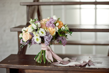 Wedding bouquet of pink roses with a lilac on a blurred background on a wooden staircase