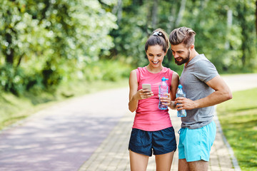 Two runners checking achievements on mobile phone app