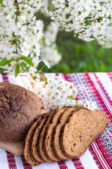 Rye bread on a wooden board against a background of with blooming cherry branches. fresh bread on a background of flowering trees