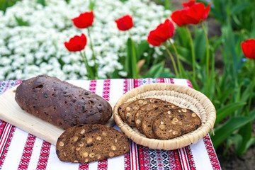 Rye bread on a wooden board against the background of spring flowers. fresh bread on a background of blooming tulips