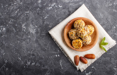 Energy ball cakes with dried apricots, sesame, linen, walnuts and dates on a black concrete  background, top view, copy space.
