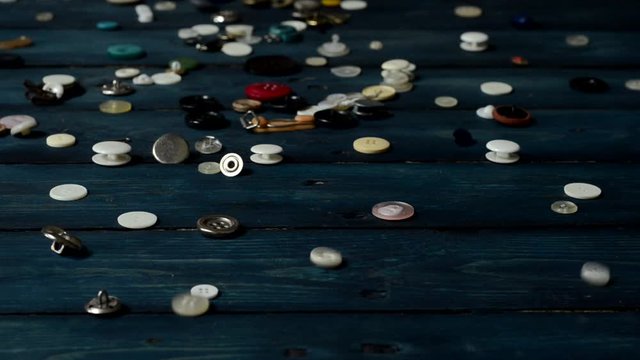 Sewing buttons falling on a wooden background