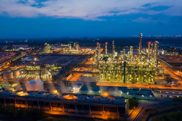 Fototapeta premium Aerial view. Oil refinery factory and oil storage tank at twilight and night. Petrochemical Industrial.