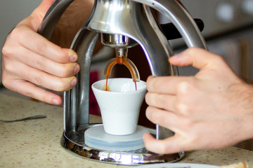 Fototapeta na wymiar Men’s hands are making coffee in the morning, healthy breakfast. Closeup. Alternative coffee machine.