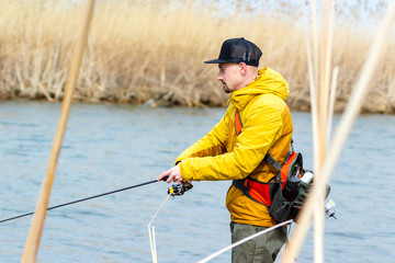 Fishing. Fisherman in a yellow jacket with fishing rod..