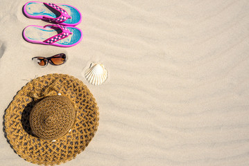Fototapeta na wymiar Flat lay vacation accessories with hat, flip flop and sunglasses on sand beach background. Summer holiday concept.